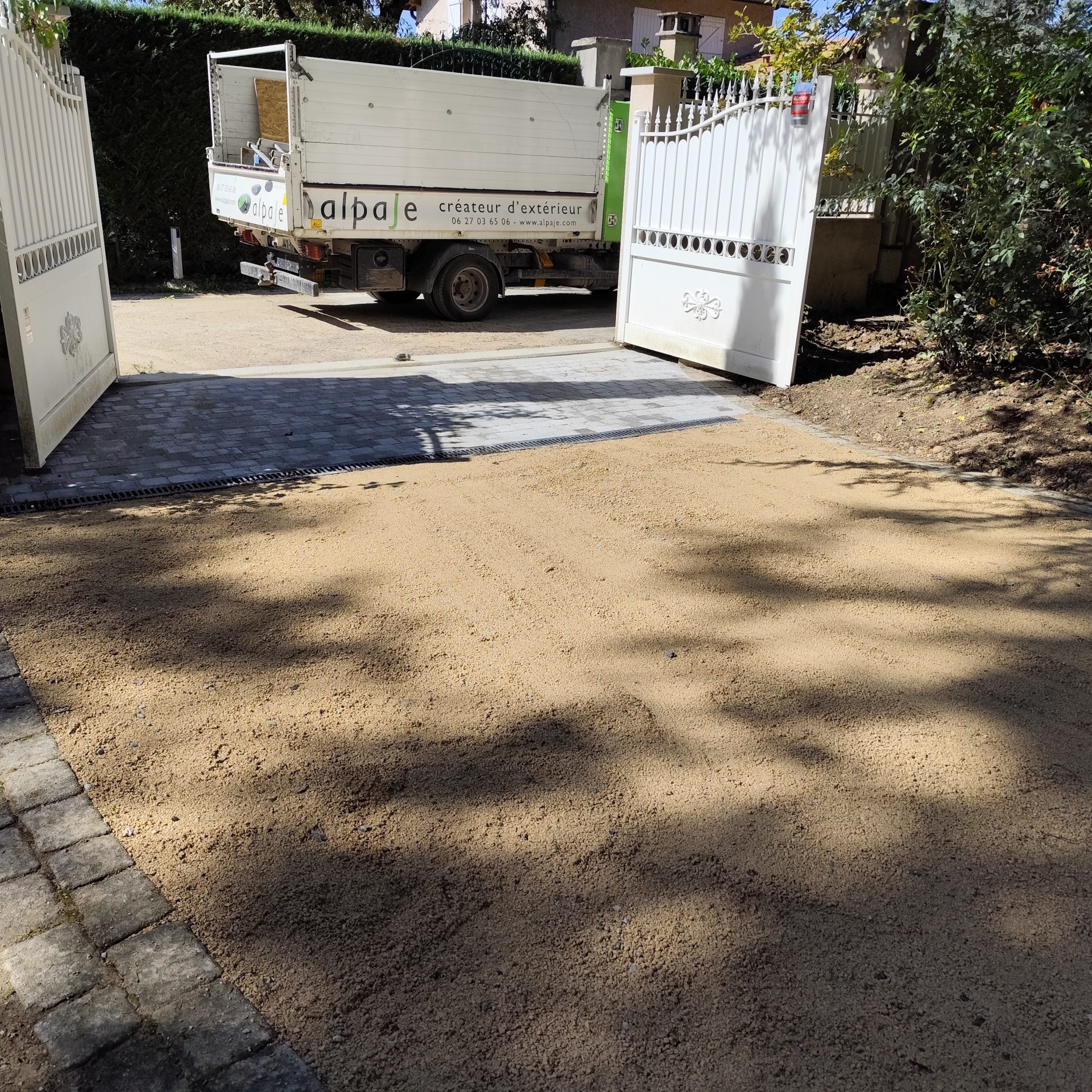 Allée en concassé calcaire.Aire de battement du portail en pavés béton mono format et caniveau de drainage